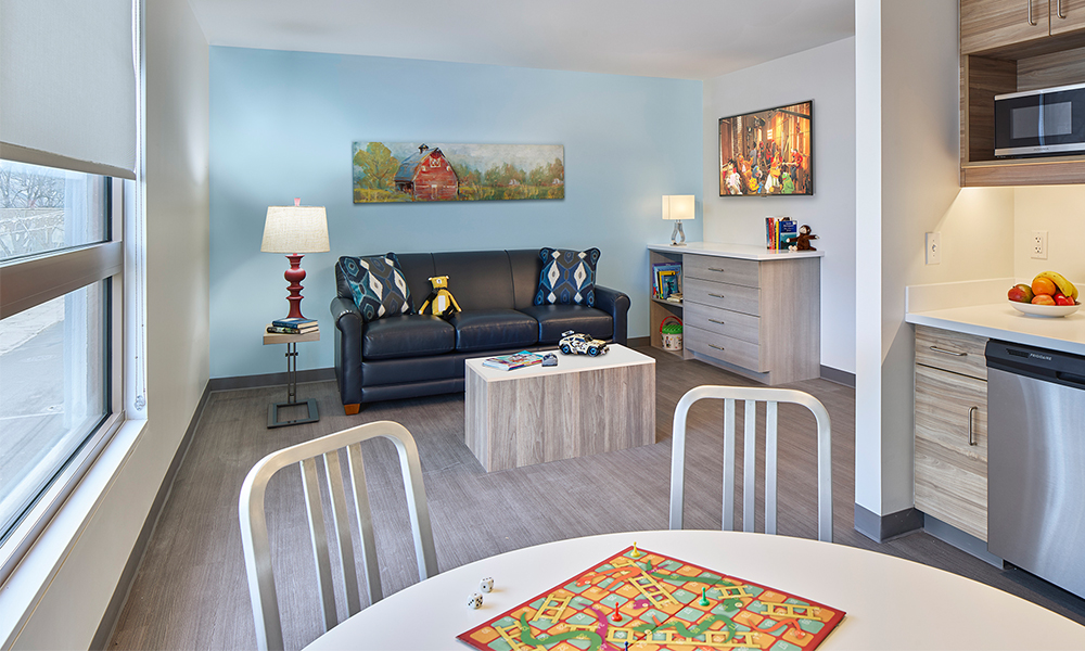 A family living space with a TV room, a full kitchenette and dining table.